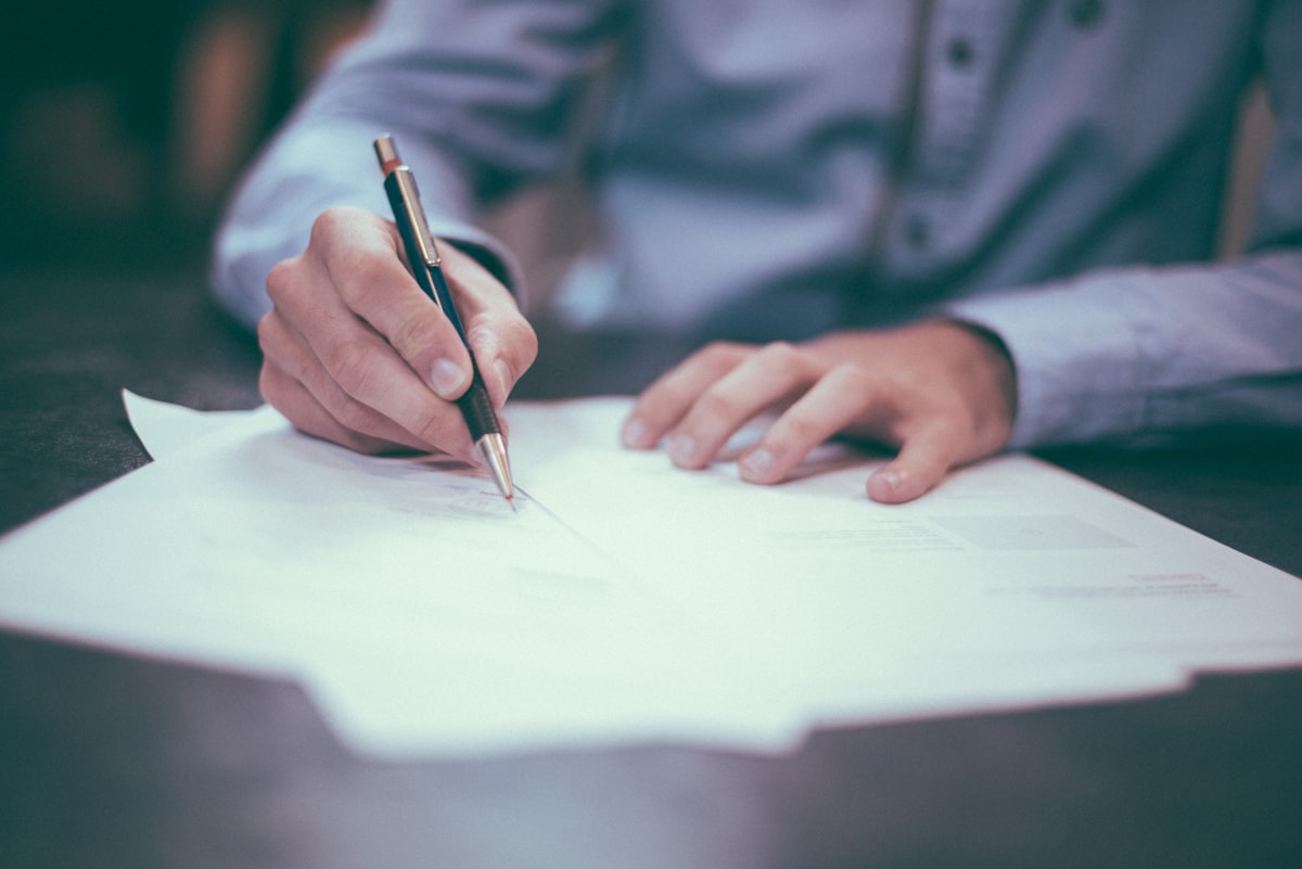 Business owner signing paperwork at a desk.