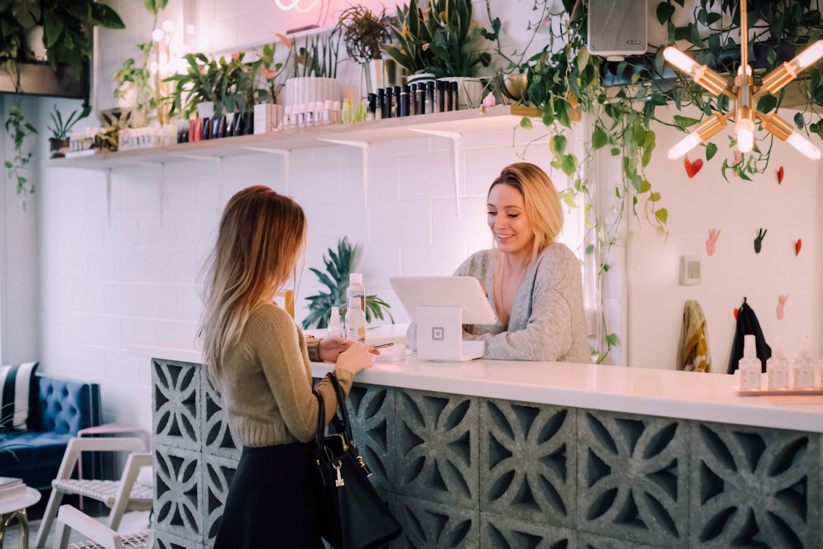 Small business owner serving a customer at the counter of her shop.