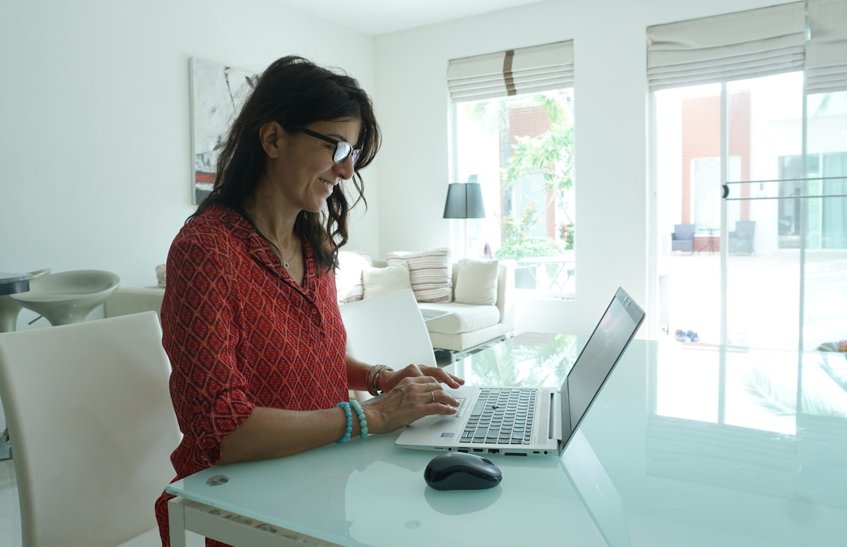 Small business owner working through her accounts on a laptop at a sunlit desk.
